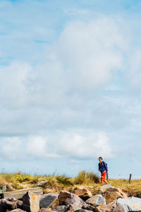 Man standing on rock against sky