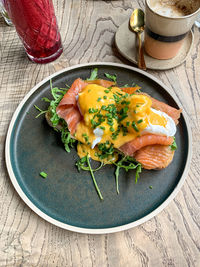 Eggs benedict with salmon and rocket on toast with latte or cappuccino coffee and red berry smoothie