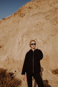 Woman wearing sunglasses standing against wall