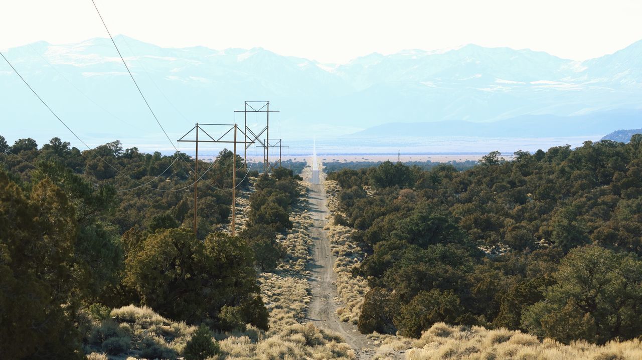 ELECTRICITY PYLON ON LANDSCAPE AGAINST SKY