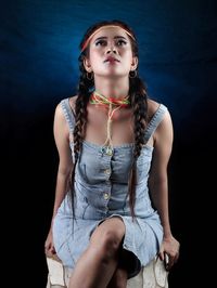 Portrait of young woman standing against blue background