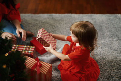 Little girl in red dress  and mother giving  christmas gifts. happy family time high angle view