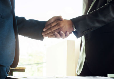 Cropped image of people with hands against white wall
