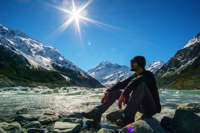 Full length of man sitting on mountain during sunny day