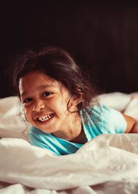 Portrait of smiling girl lying on bed at home