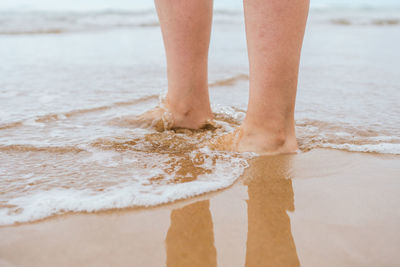 Close-up of female caucasian feet walking on the sand on the shore of the beach