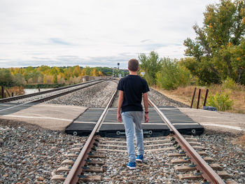 Rear view of man standing on railroad track