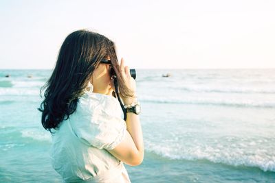 Woman standing at beach against sky