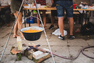 Low section of people standing by food getting prepared in container