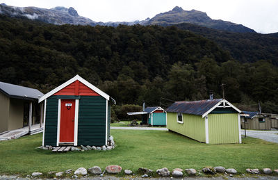 Houses on field by green mountain