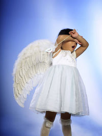 Girl in angel costume against purple background