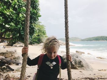 Boy standing on beach by sea