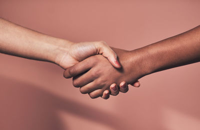 Cropped hand of woman against yellow wall