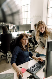 Female coworker using computer while entrepreneur discussing in office