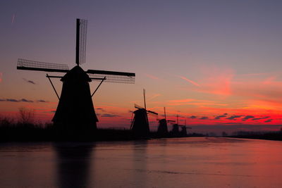 Silhouette cranes against sky during sunset