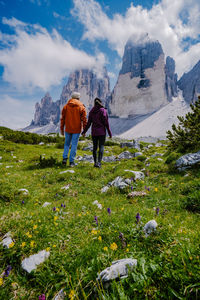 Rear view of women standing on mountain against sky