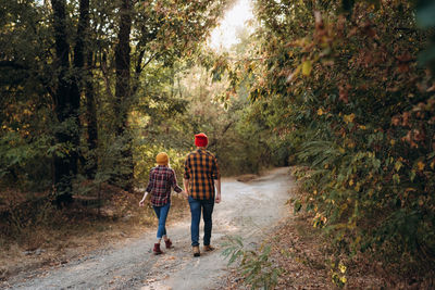 Rear view of friends walking on footpath in forest