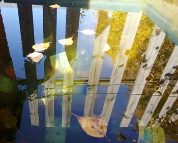 Reflection of fence on glass against sky