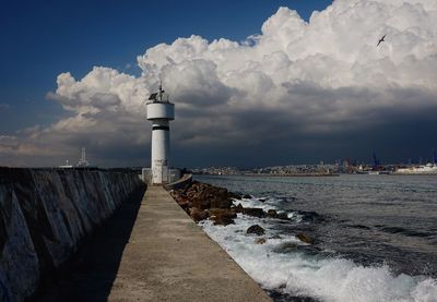 Lighthouse by sea against sky