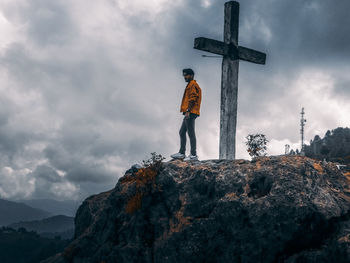 Low angle view of man standing on rock against sky