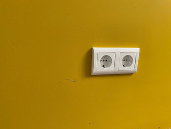 Close-up of telephone mounted on yellow wall