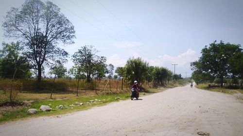Man riding bicycle on road against sky