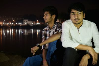 Young men sitting in city at night