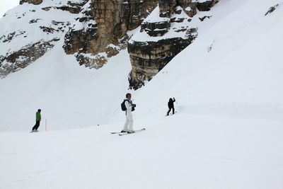 Men wearing ski-wear standing on snow covered field