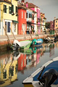 Boats moored in canal by houses in city