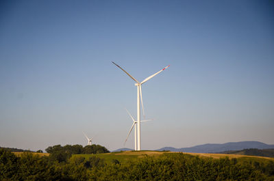 Wind turbines on field against clear sky