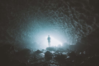 Silhouette man standing by sea against sky at night