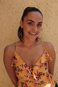 Portrait of smiling young woman standing against wall