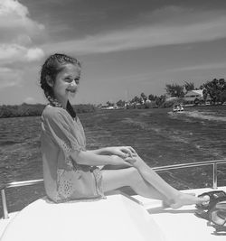 Smiling girl sitting in boat on sea