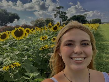 Portrait of young woman standing amidst sunflowers