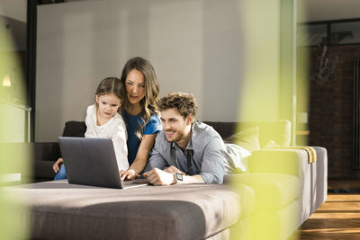 Family using laptop on sofa at home