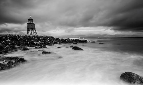 Lighthouse by sea against sky