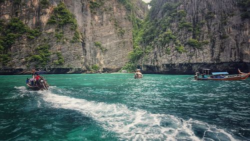 People on boat by river against mountains