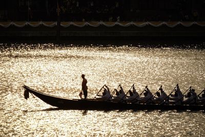 Silhouette people on boat in water