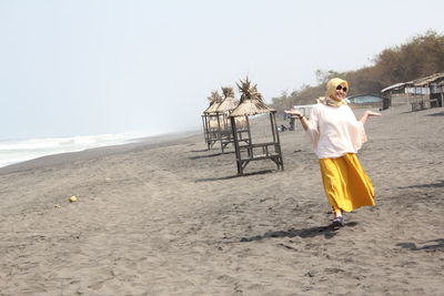 Full length of woman walking on beach against sky