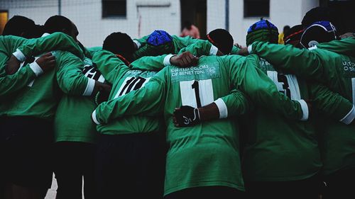 Men huddling while standing outdoors