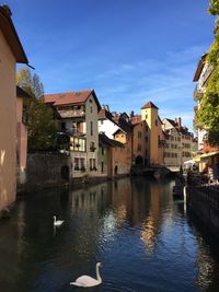 Buildings by river against sky in city