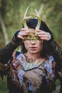 Portrait of young woman holding mask