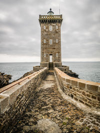 View of lighthouse by sea against sky