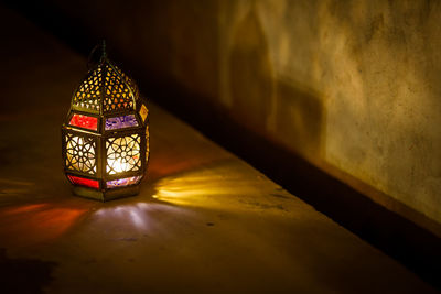 Illuminated electric lamp on building wall