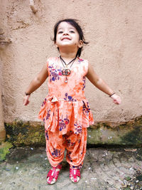 Cute smiling girl standing against wall