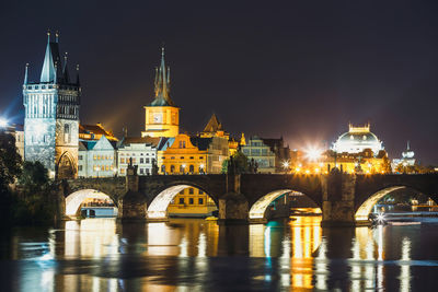 Arch bridge over river in city at night