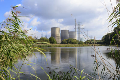 Coal-fired power station by lippe river against cloudy sky