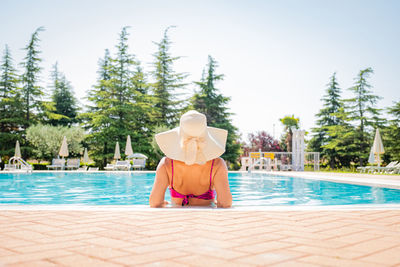 Young blonde woman relaxing in swimming pool at spa resort - relaxing concept