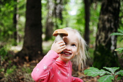 Portrait of girl with mushroom standing in forest