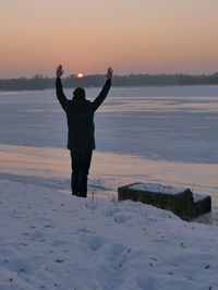 Full length of silhouette man standing on snow covered landscape during sunset